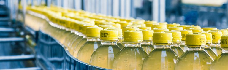 Een productielijn met olie in transparante flessen met een gele dop. 