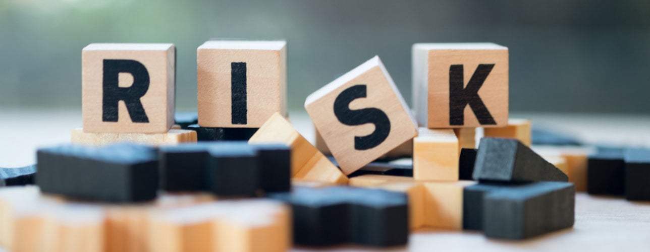 Het woord RISK op vier houten dobbelstenen, samen met andere houten speelstenen