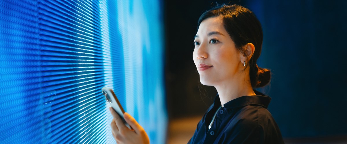 Vrouw met smartphone staande voor LED-wand