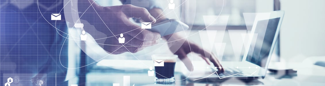 Iemand die een smartphone vasthoudt en op een laptop typt.