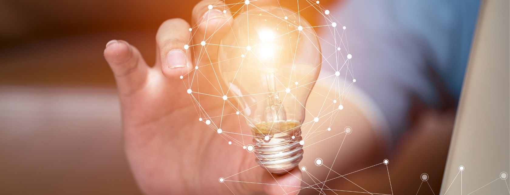 Hand houdt een gloeiende gloeilamp vast, symboliseert innovatie en creativiteit.